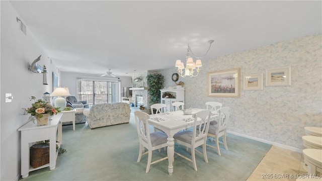 tiled dining room featuring a fireplace, visible vents, wallpapered walls, baseboards, and ceiling fan with notable chandelier