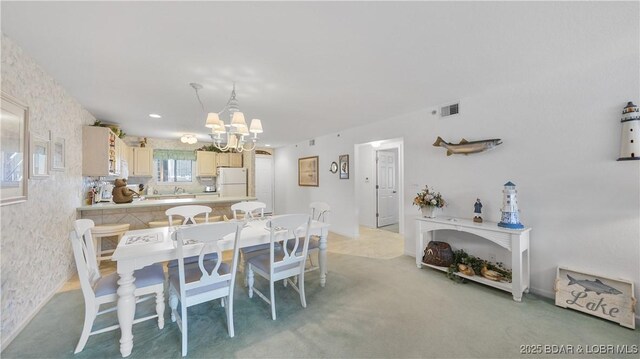 dining room with a chandelier, visible vents, and light colored carpet