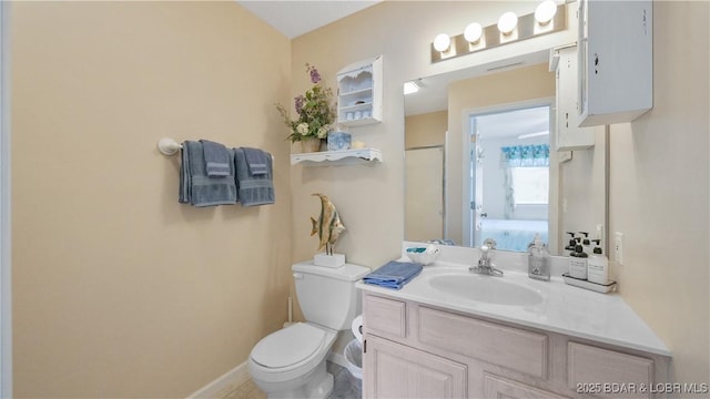 bathroom featuring toilet, baseboards, and vanity