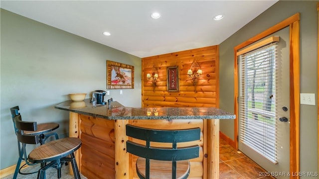 bar with baseboards, tile patterned flooring, wet bar, log walls, and recessed lighting