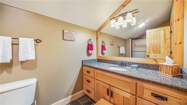 bathroom featuring tile patterned flooring, toilet, vanity, baseboards, and vaulted ceiling