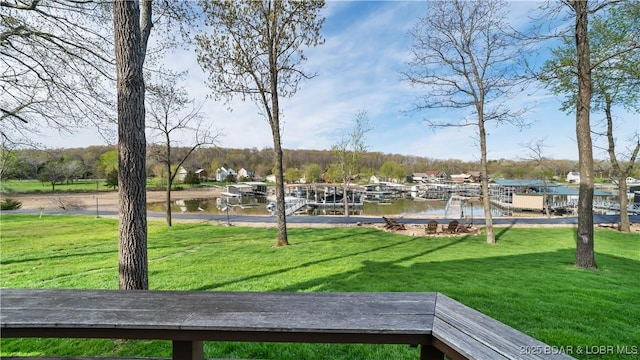 view of property's community with a water view, a yard, and a boat dock