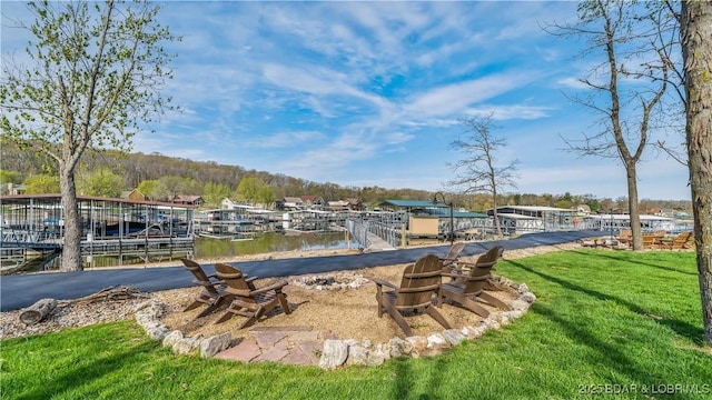 exterior space featuring a dock, a water view, boat lift, and a yard