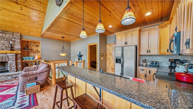 kitchen featuring wood ceiling, stainless steel microwave, a peninsula, fridge with ice dispenser, and backsplash