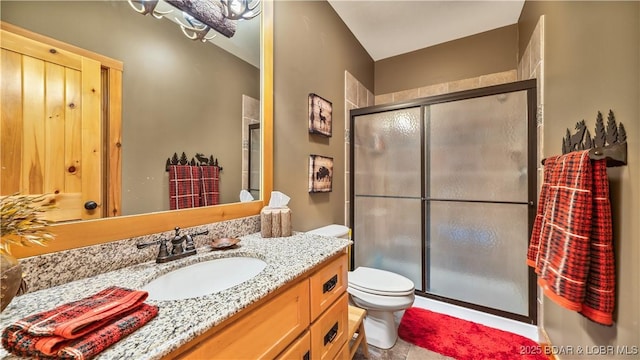 bathroom featuring toilet, a shower stall, and vanity