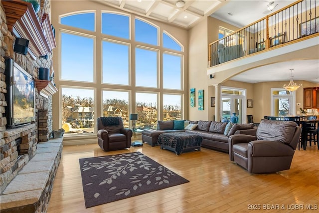 living room with arched walkways, decorative columns, light wood-type flooring, coffered ceiling, and beamed ceiling