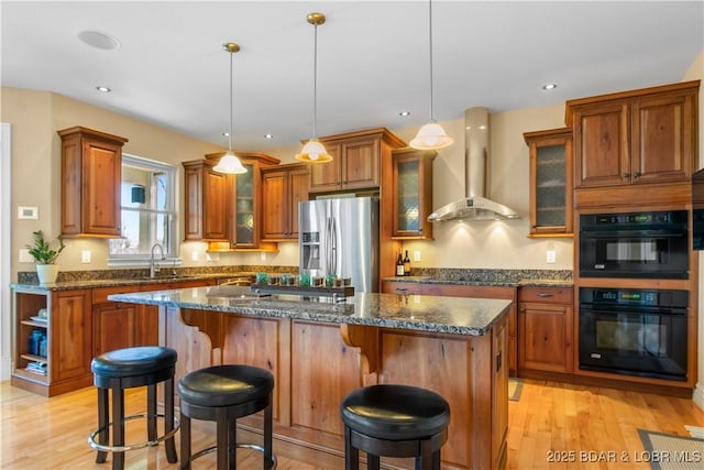 260 Greystone Ln, Villages, MO 65079 - kitchen featuring brown cabinetry, a sink, wall chimney range hood, a kitchen island, and black appliances