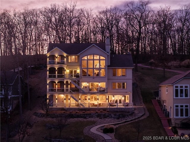 260 Greystone Ln, Villages, MO 65079 - back of house at dusk with stairway, a chimney, and a balcony