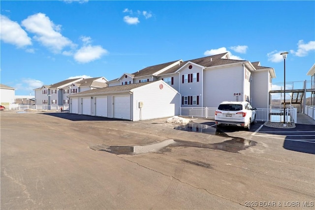 view of front of property with a residential view, community garages, and an outbuilding