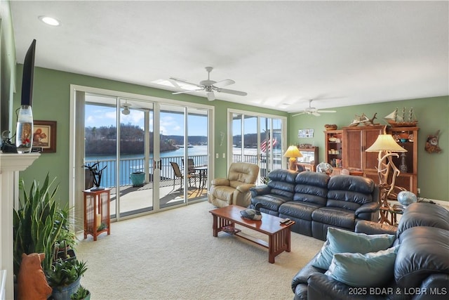 living area featuring carpet floors, a water view, and a ceiling fan