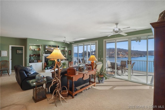 living room featuring a water view, a ceiling fan, and carpet flooring