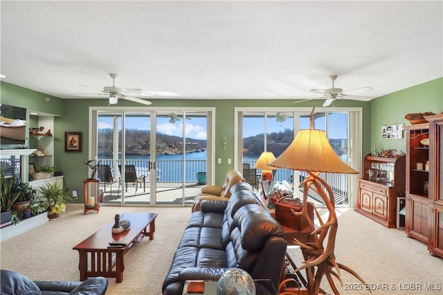 carpeted living area featuring a water view, baseboards, and a ceiling fan