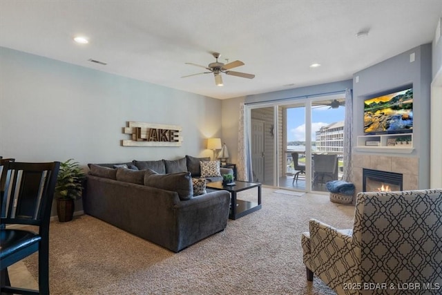 carpeted living room with ceiling fan, a fireplace, visible vents, and recessed lighting