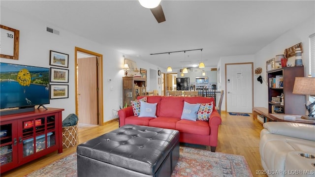 living room with a ceiling fan, visible vents, track lighting, and wood finished floors