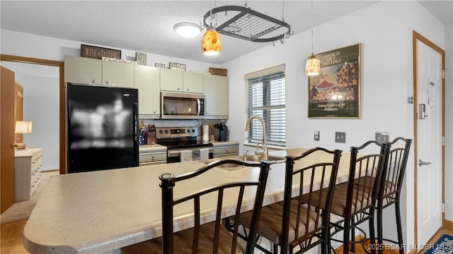 kitchen with a sink, light countertops, appliances with stainless steel finishes, tasteful backsplash, and decorative light fixtures