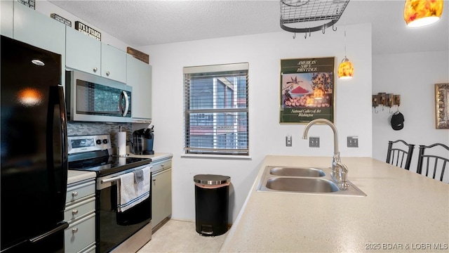 kitchen featuring a textured ceiling, a peninsula, a sink, appliances with stainless steel finishes, and tasteful backsplash