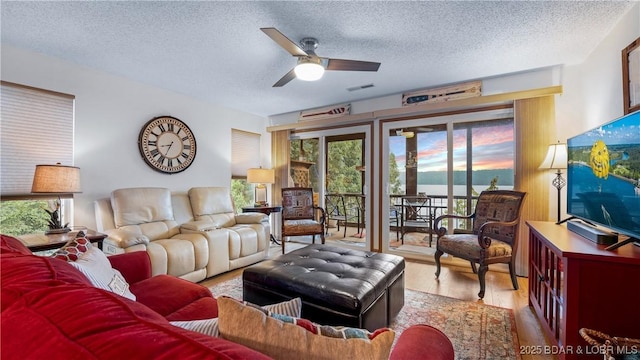 living area with a healthy amount of sunlight, a textured ceiling, visible vents, and wood finished floors