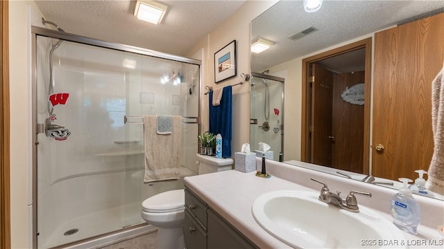 bathroom with a stall shower, visible vents, toilet, a textured ceiling, and vanity