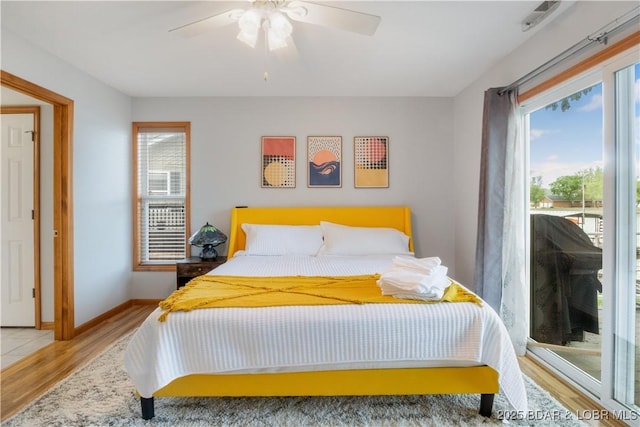 bedroom featuring multiple windows, wood finished floors, a ceiling fan, and baseboards