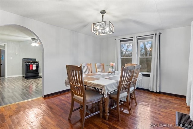 dining room featuring arched walkways, visible vents, an inviting chandelier, wood finished floors, and baseboards