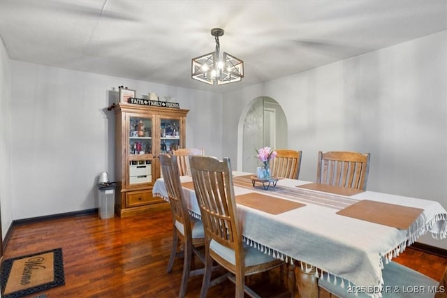 dining space featuring baseboards, a notable chandelier, arched walkways, and wood finished floors