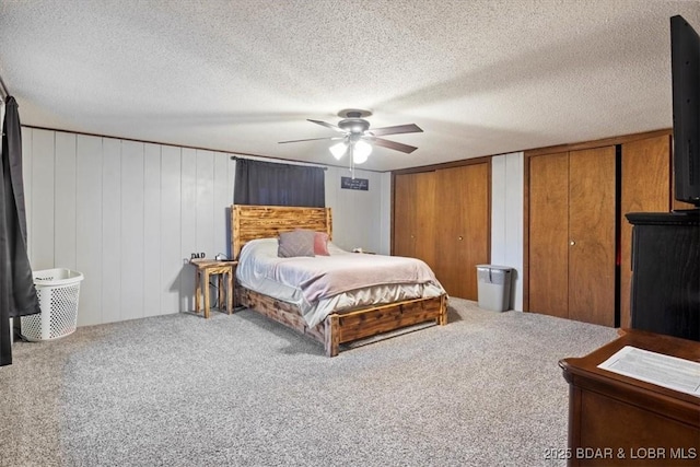 carpeted bedroom featuring multiple closets, ceiling fan, and a textured ceiling