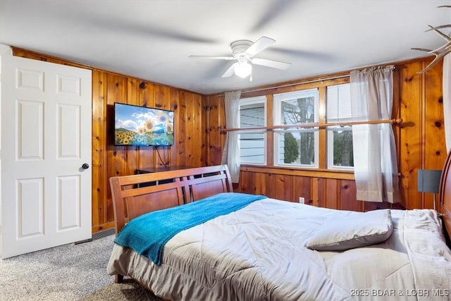 carpeted bedroom with ceiling fan and wooden walls