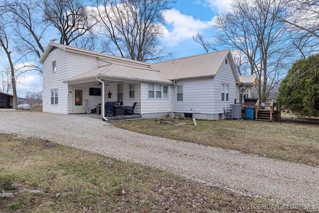 view of front of house featuring driveway, metal roof, and a front yard