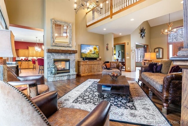 living room with a high ceiling, a multi sided fireplace, wood finished floors, baseboards, and an inviting chandelier