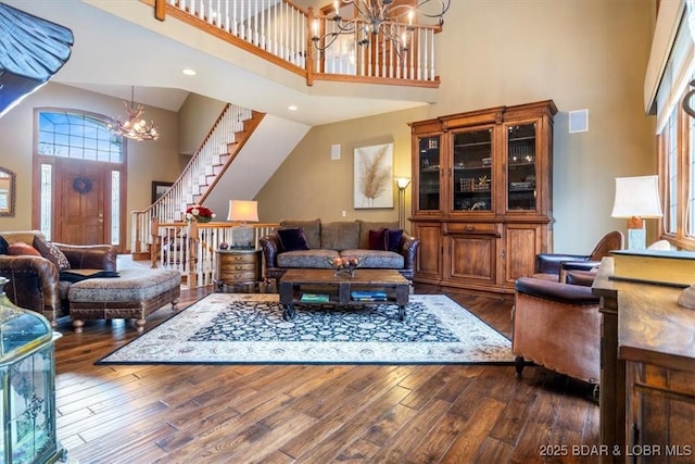 living area featuring an inviting chandelier, stairs, dark wood-style flooring, a towering ceiling, and recessed lighting
