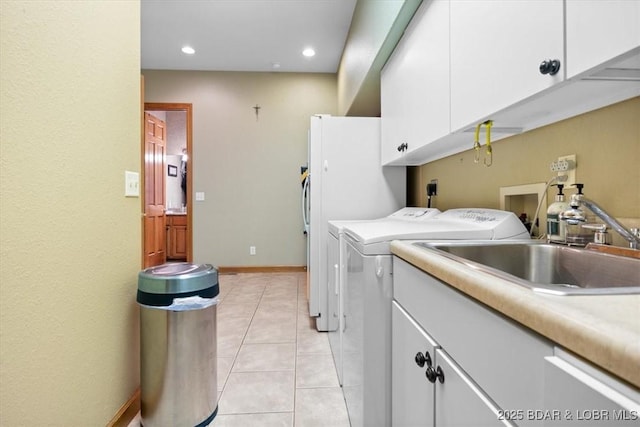 clothes washing area featuring cabinet space, light tile patterned floors, washer and dryer, a sink, and recessed lighting