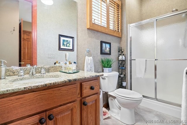 bathroom with a stall shower, vanity, toilet, and tile patterned floors