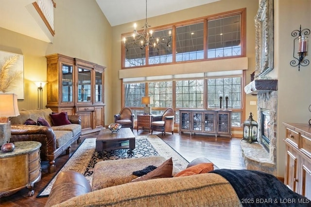 living area with a notable chandelier, high vaulted ceiling, wood finished floors, and a glass covered fireplace