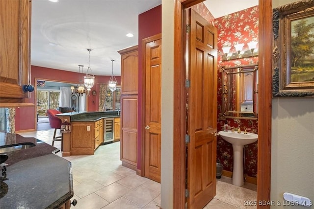 interior space featuring a chandelier, wine cooler, a sink, and wallpapered walls