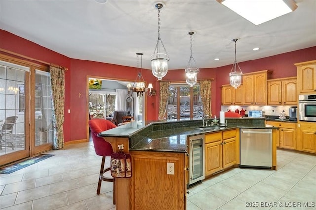 kitchen with wine cooler, stainless steel appliances, a kitchen island with sink, a sink, and a kitchen breakfast bar