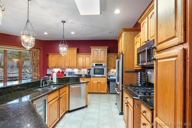 kitchen featuring tasteful backsplash, appliances with stainless steel finishes, dark stone countertops, pendant lighting, and a sink