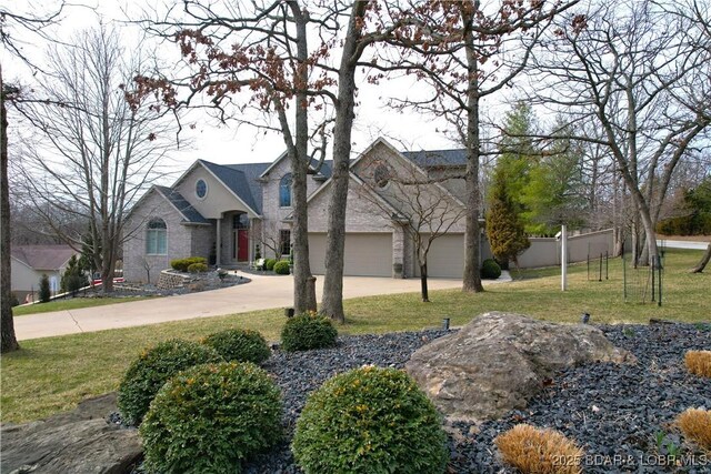 view of front of property featuring a garage, fence, driveway, stone siding, and a front lawn