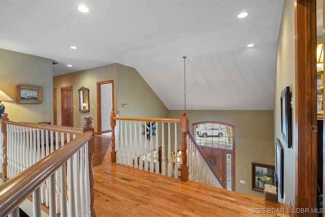 hallway with wood finished floors, an upstairs landing, lofted ceiling, and recessed lighting