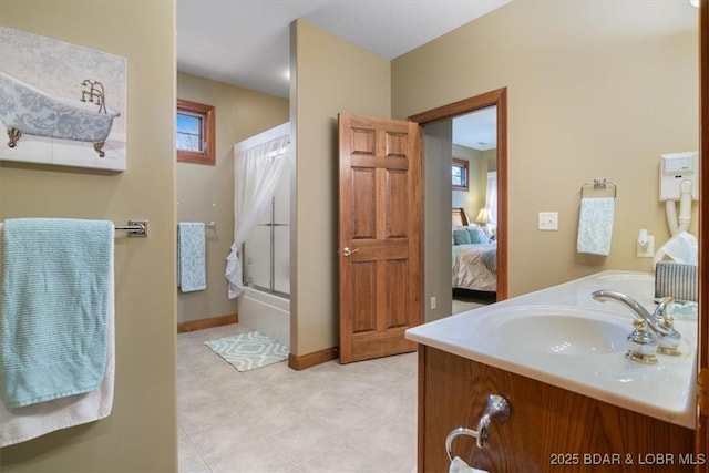 ensuite bathroom featuring a shower with door, vanity, baseboards, and ensuite bathroom