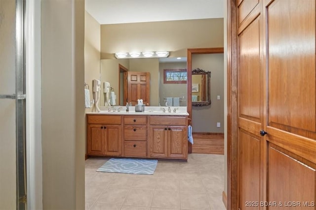 full bath with double vanity, baseboards, and a sink