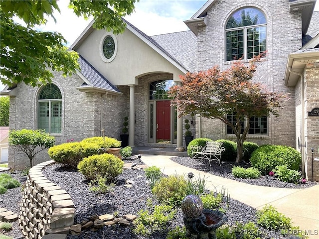 view of exterior entry featuring brick siding and roof with shingles