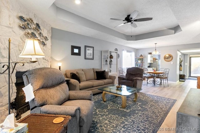71 Costa Del Sol Dr Unit 207, Lake Ozark, MO 65049 - living room with baseboards, a ceiling fan, a textured ceiling, a tray ceiling, and wood finished floors