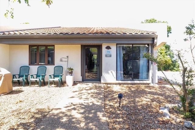 rear view of house with a tiled roof and stucco siding