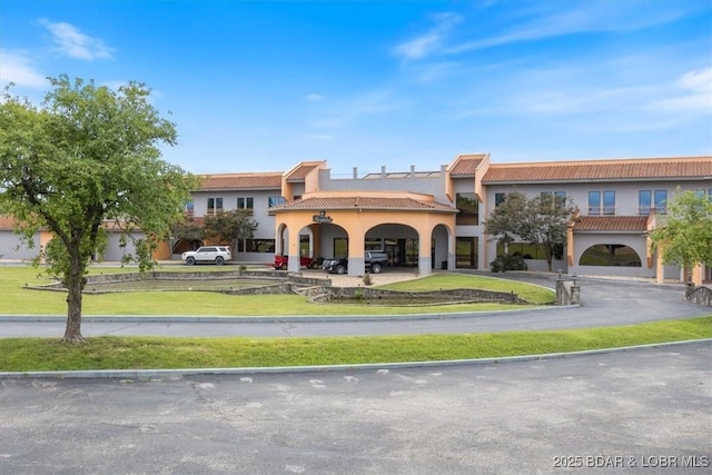 exterior space with driveway, a tiled roof, a front lawn, and stucco siding