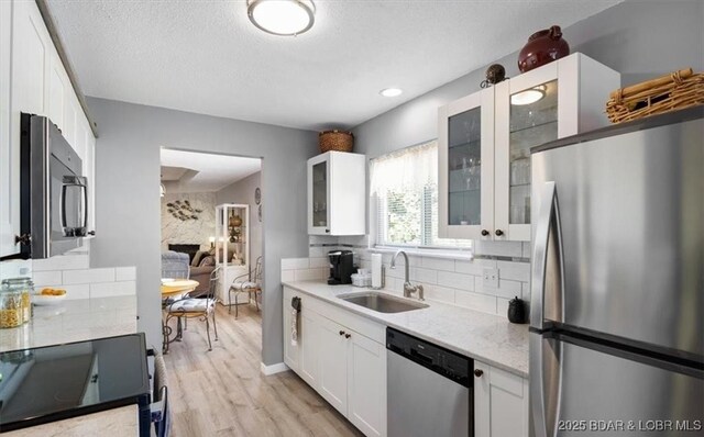 71 Costa Del Sol Dr Unit 207, Lake Ozark, MO 65049 - kitchen featuring tasteful backsplash, white cabinets, a sink, appliances with stainless steel finishes, and light wood-type flooring