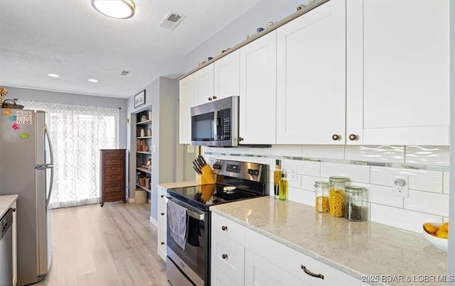 71 Costa Del Sol Dr Unit 207, Lake Ozark, MO 65049 - kitchen with light wood-style flooring, white cabinets, visible vents, decorative backsplash, and stainless steel appliances