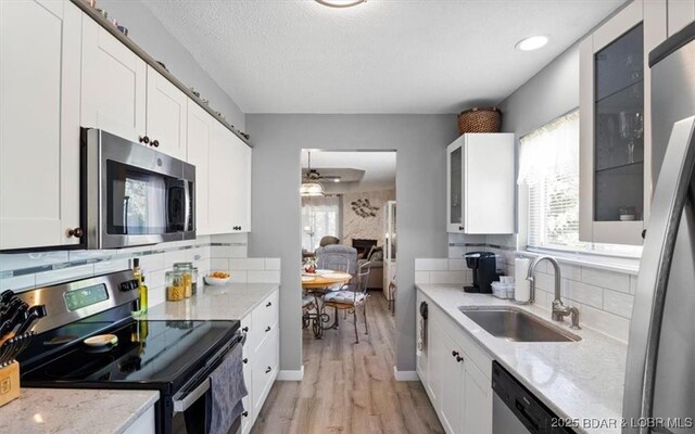 71 Costa Del Sol Dr Unit 207, Lake Ozark, MO 65049 - kitchen with light wood-style flooring, white cabinets, appliances with stainless steel finishes, light stone counters, and a sink