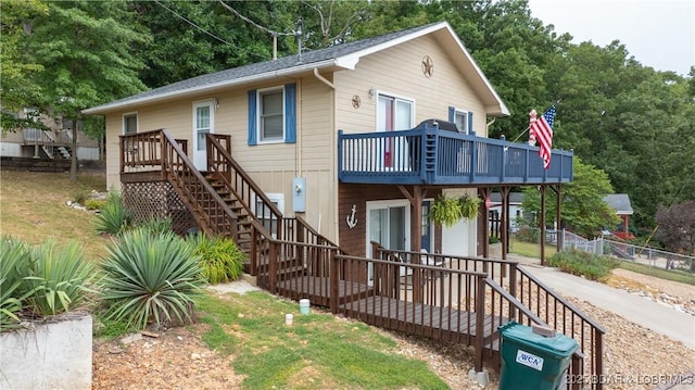 view of front of property featuring a deck, stairs, and fence