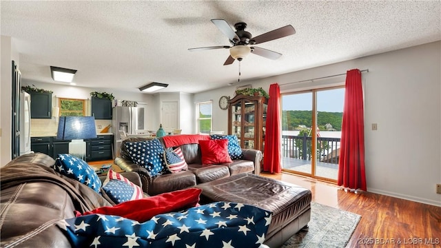 living room with a ceiling fan, light wood-type flooring, a healthy amount of sunlight, and a textured ceiling