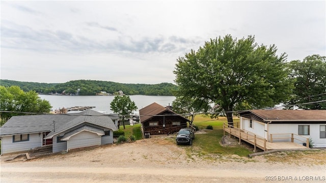 view of front of property featuring dirt driveway and a water view